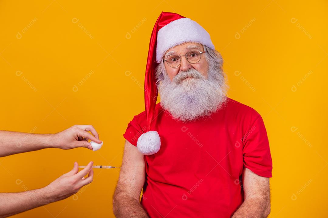 Papai Noel sendo vacinado com injeção.