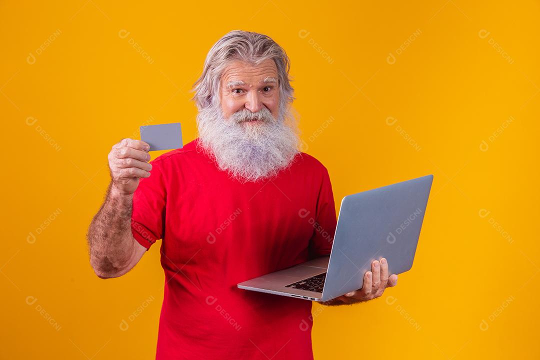 Homem em fundo amarelo mostrando cartão e fazendo uma chamada de vídeo no laptop