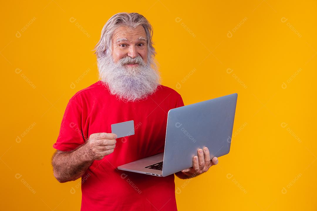 Homem idoso segurando computador portátil e cartão de crédito bancário. Transação de compras on-line. Método sem dinheiro de banco móvel.