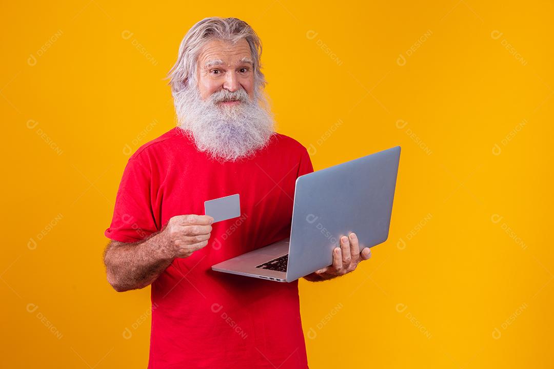 Homem idoso segurando computador portátil e cartão de crédito bancário. Transação de compras on-line. Método sem dinheiro de banco móvel.