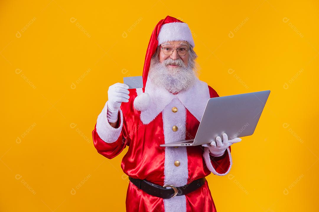 Papai Noel Mostrando um cartão e numa chamada no Laptop