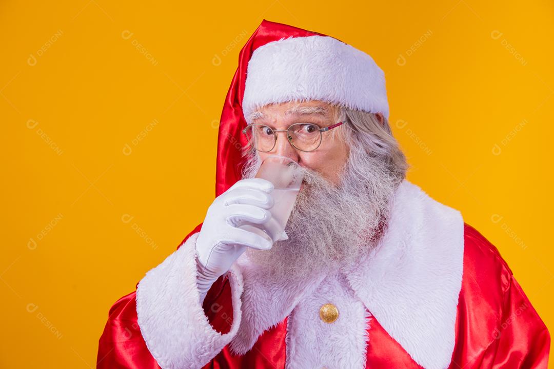 Papai Noel bebendo um copo de água no fundo amarelo