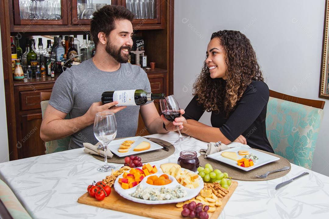 Casal no jantar romântico degustação de vinho e queijo.