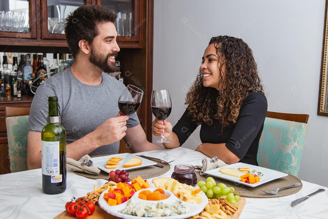Casal no jantar romântico degustação de vinho e queijo.