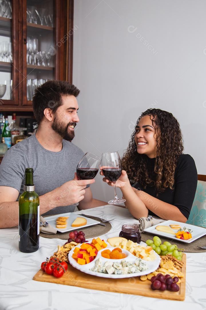 Casal no jantar romântico degustação de vinho e queijo.