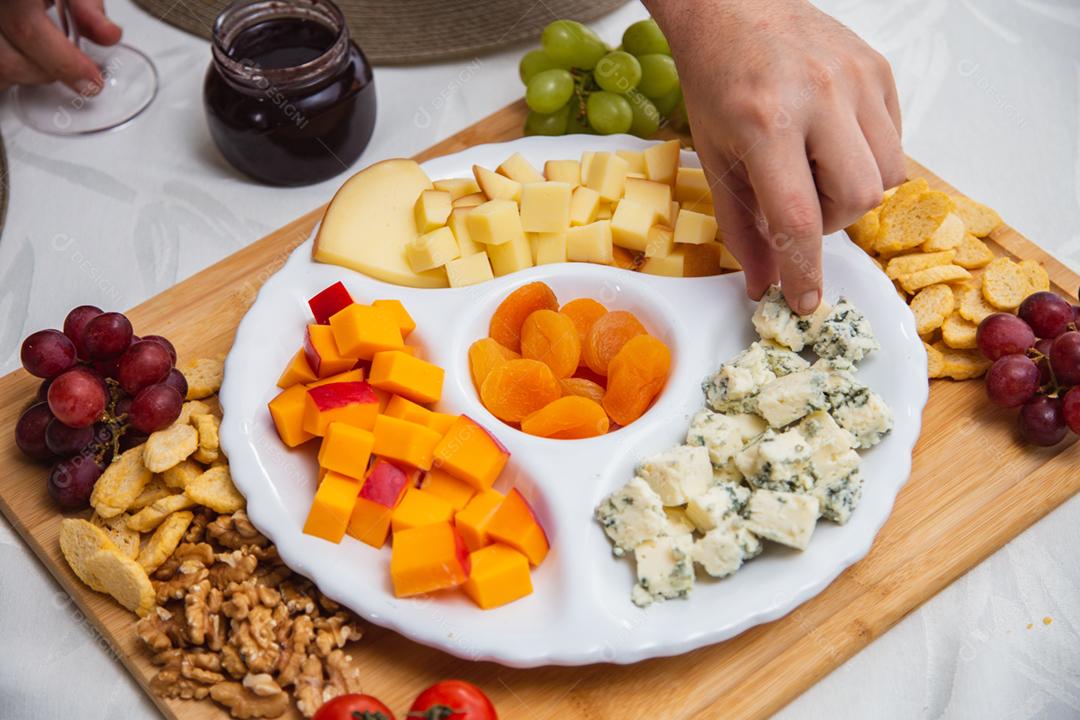 Prato de queijo com variedade de aperitivos na mesa.