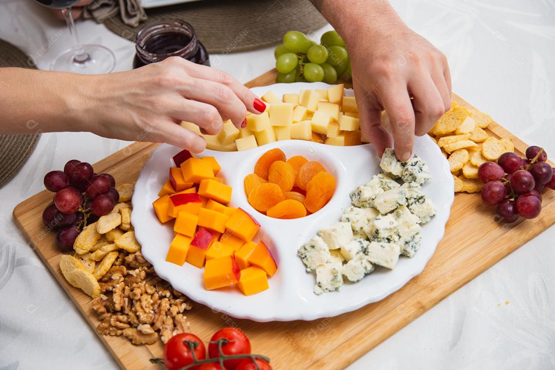 Prato de queijo com variedade de aperitivos na mesa.