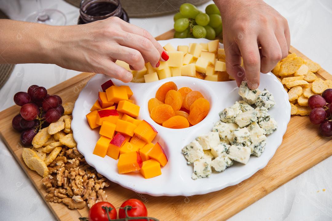 Prato de queijo com variedade de aperitivos na mesa.