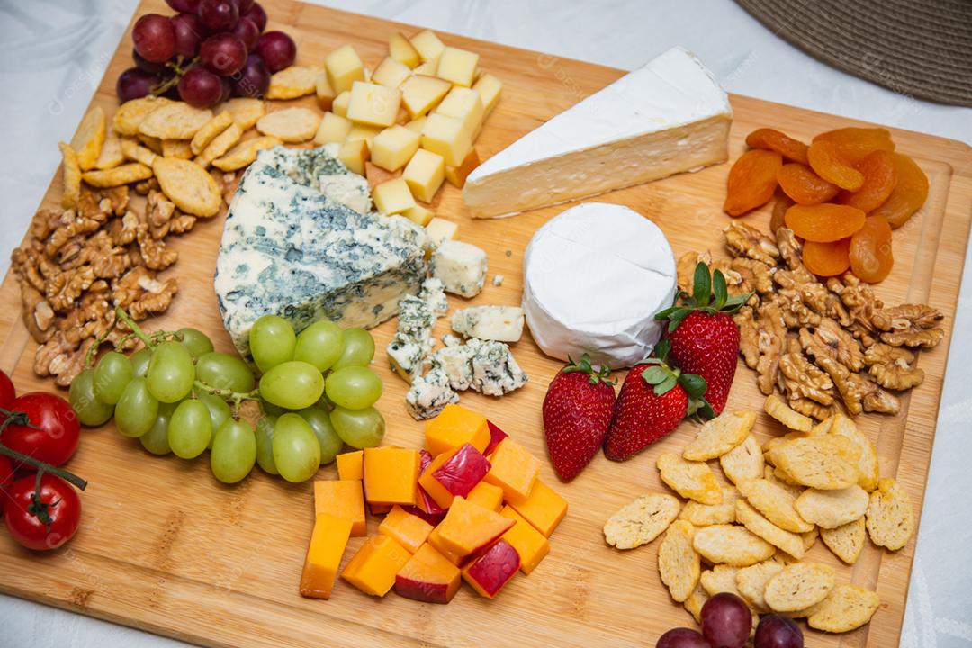 Prato de queijo com variedade de aperitivos na mesa.