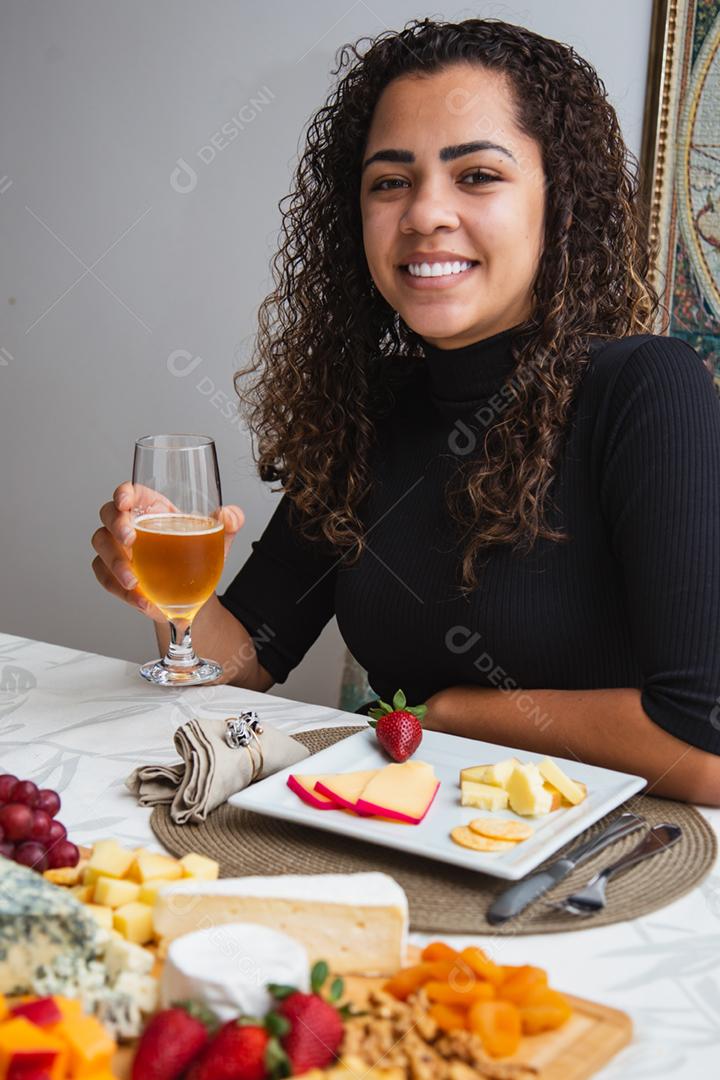 Mulher saboreando Prato de queijo com variedade de aperitivos na mesa.