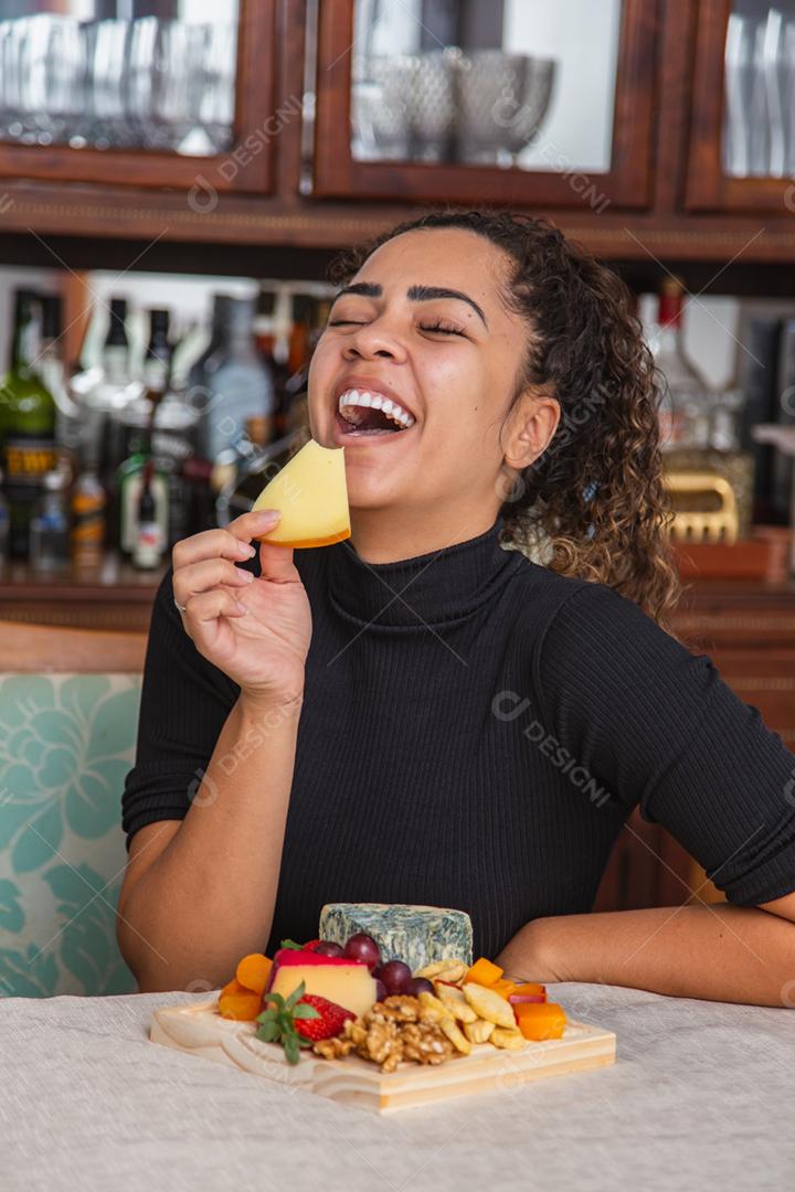 jovem comendo queijo. mulher comendo salgadinhos de queijo
