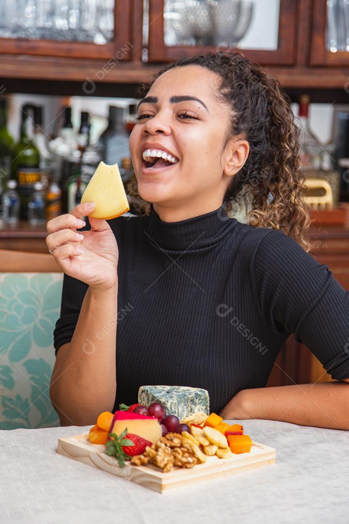 jovem comendo queijo. mulher comendo salgadinhos de queijo