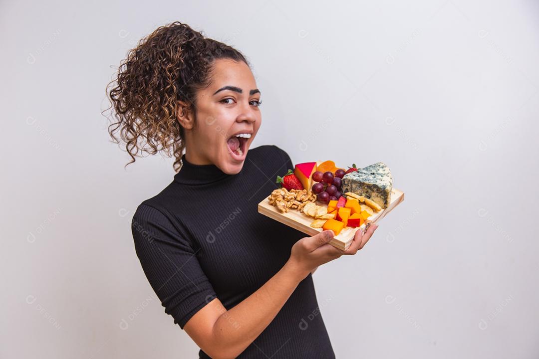 jovem segurando uma tábua com vários tipos de queijo de lanches.