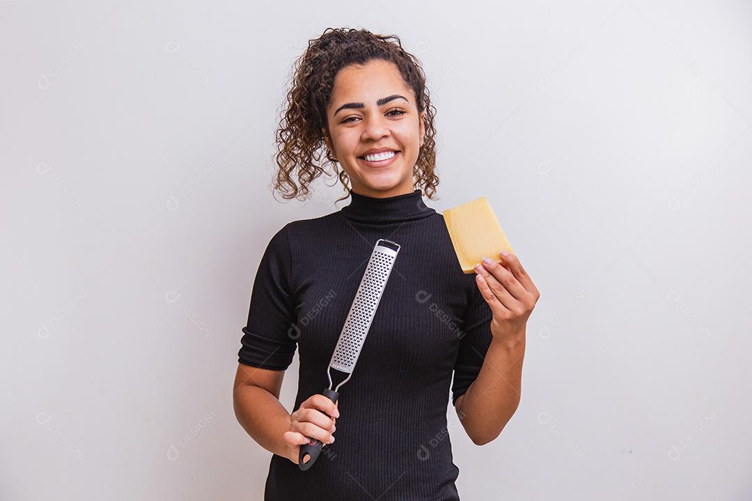 Mulher segurando um ralador e uma fatia de queijo na mão