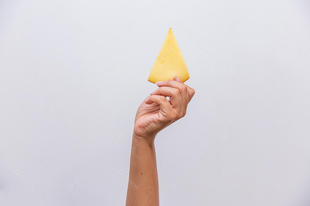 Mão segurando um pedaço de queijo provolone.