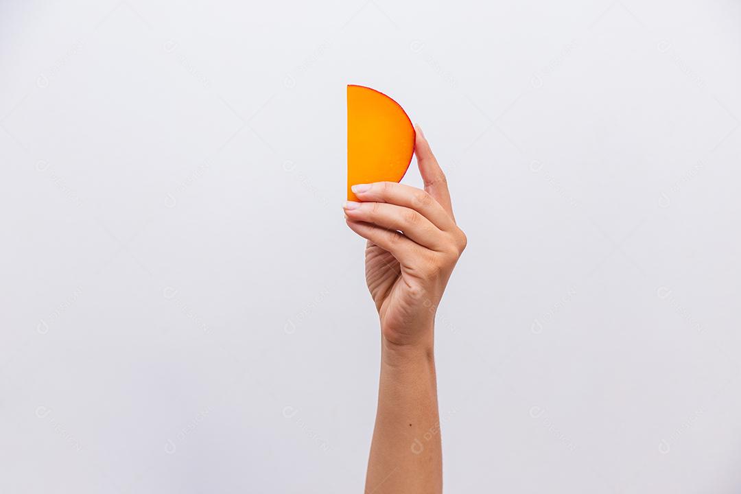 Mão segurando um pedaço de queijo Edam.