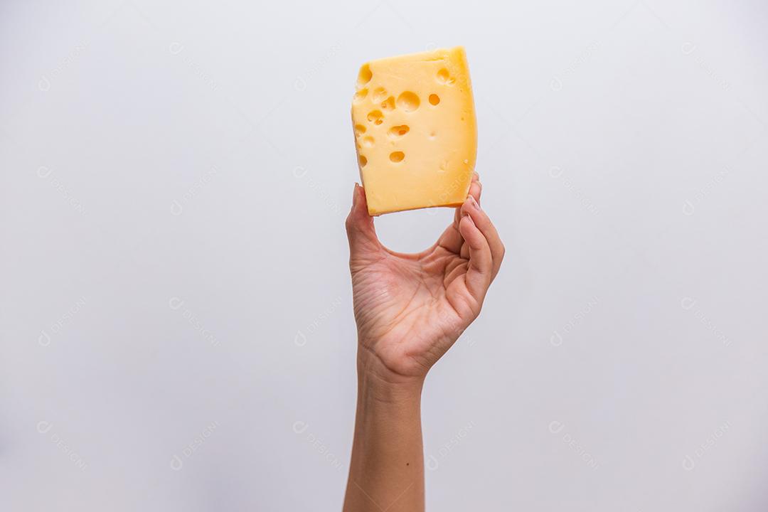 mão segurando um pedaço de queijo elementar.