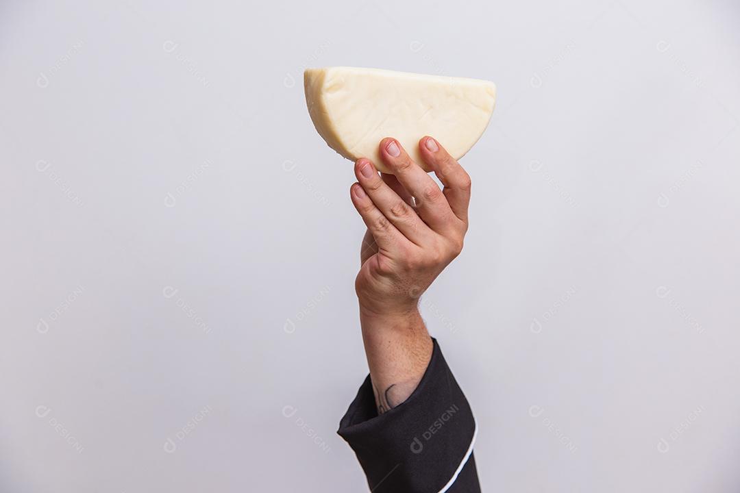 Mão segurando um pedaço de queijo .