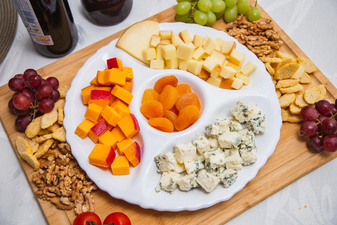 Prato de queijo com variedade de aperitivos na mesa.