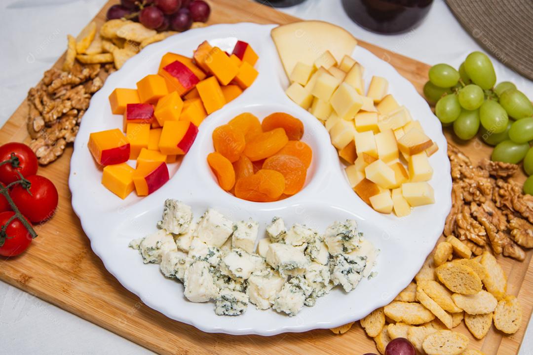 Prato de queijo com variedade de aperitivos na mesa.
