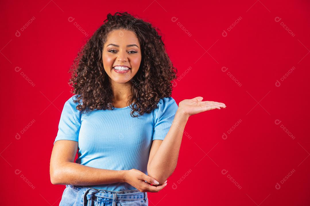 Alegre mulher afro aponta para o espaço da cópia, discute incrível