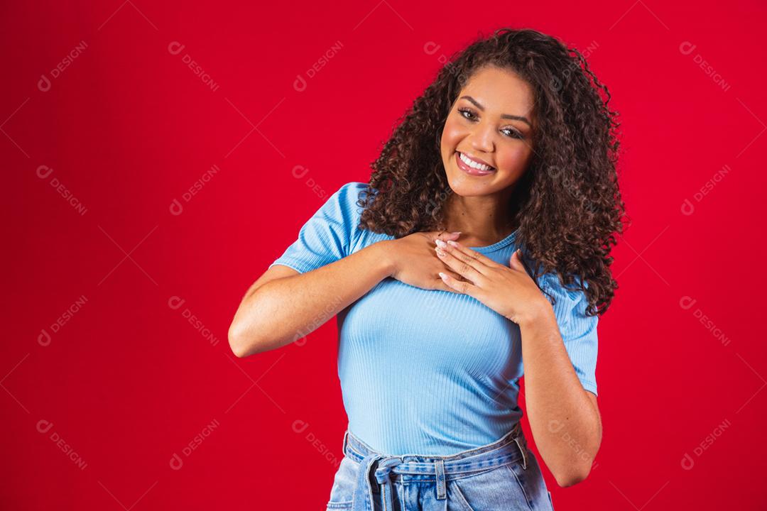 Grata e esperançosa mulher negra feliz segurando as mãos no peito sentindo