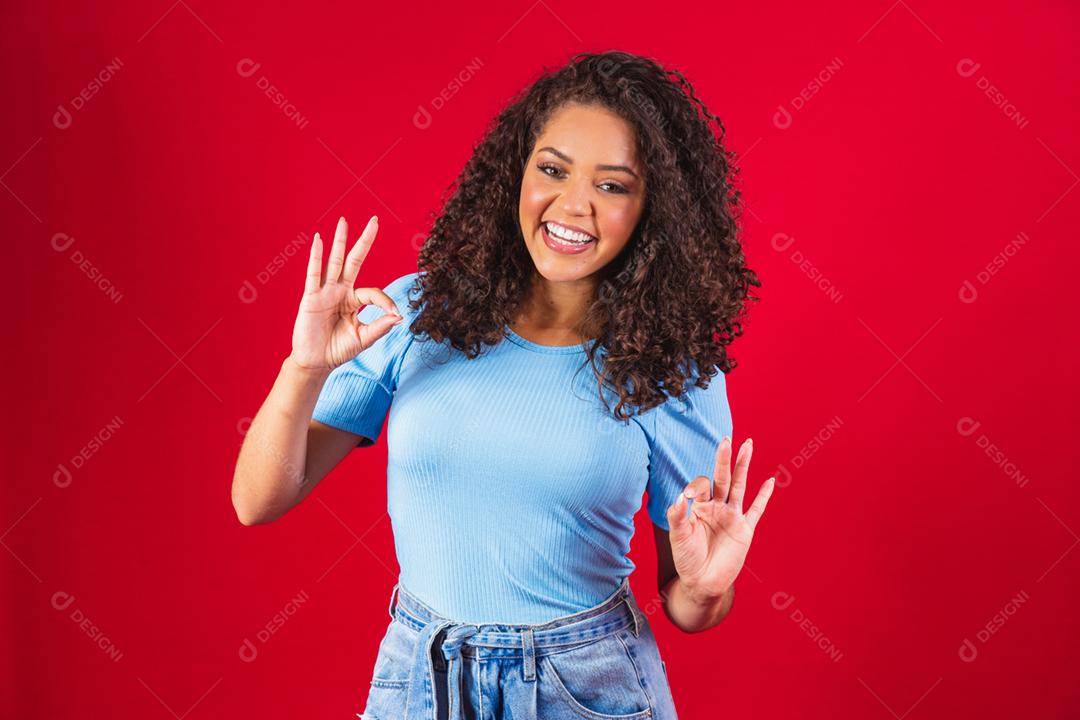 Sorrindo jovem afro fazendo sinal de ok.