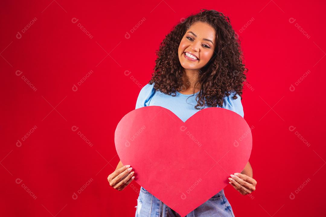 garota afro segurando nas mãos forma de coração amour isolado sobre vermelho