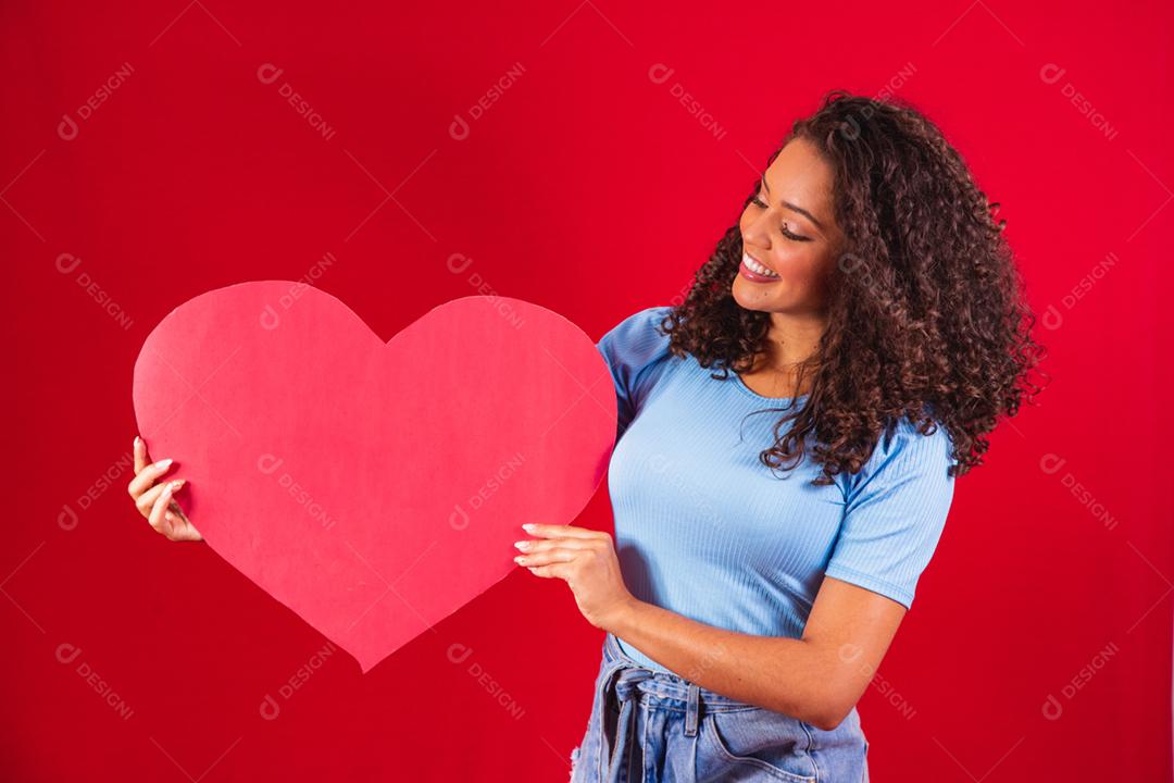 garota afro segurando nas mãos forma de coração amour isolado sobre vermelho