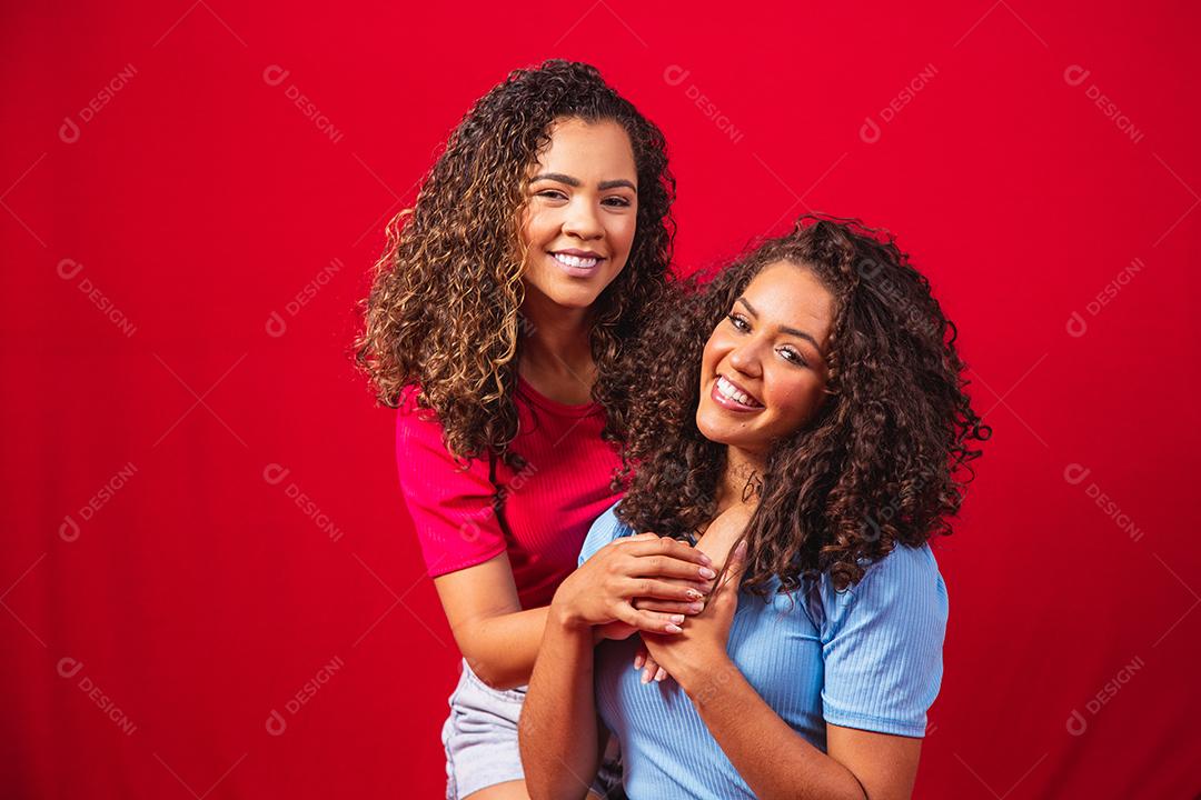 Retrato de casal de lésbicas jovens mulheres afro sobre fundo vermelho. conceito LGBT