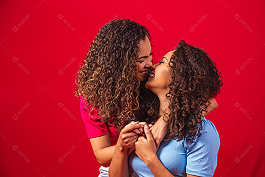 Retrato de casal de lésbicas jovens mulheres afro sobre fundo vermelho. conceito LGBT