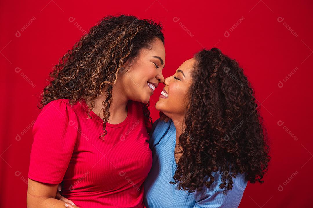 Retrato de casal de lésbicas jovens mulheres afro sobre fundo vermelho. conceito LGBT