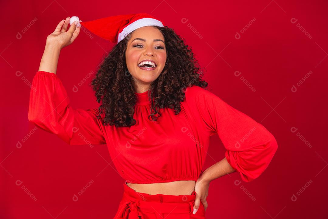 Feche a foto de uma jovem afro usando chapéu de Papai Noel isolado sobre fundo vermelho.