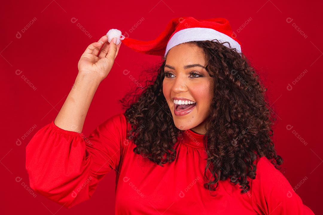 Feche a foto de uma jovem afro usando chapéu de Papai Noel isolado sobre fundo vermelho.