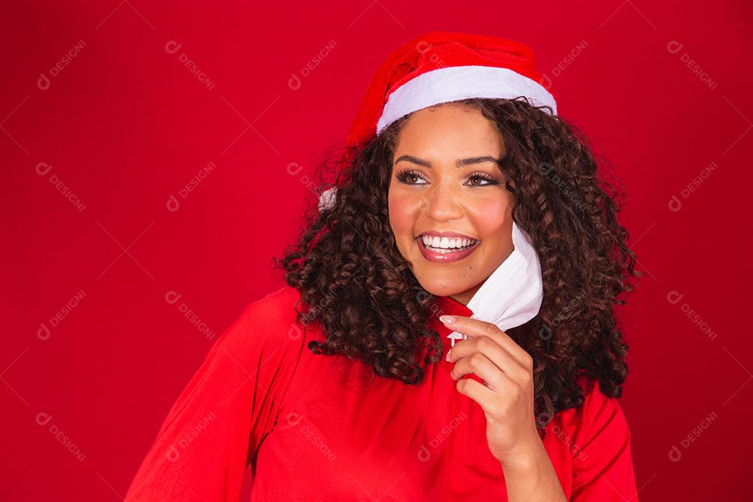 Fim da pandemia no Natal. Mulher tirando sua máscara com chapéu de Papai Noel