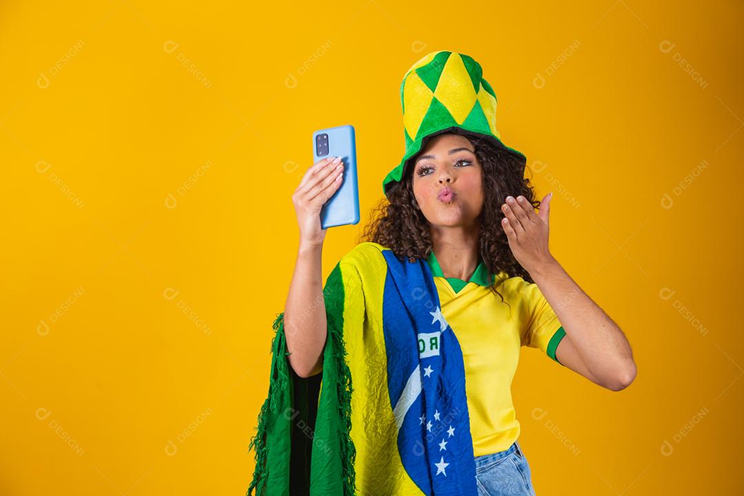 Garota afro torcendo pelo time brasileiro, segurando bandeira nacional