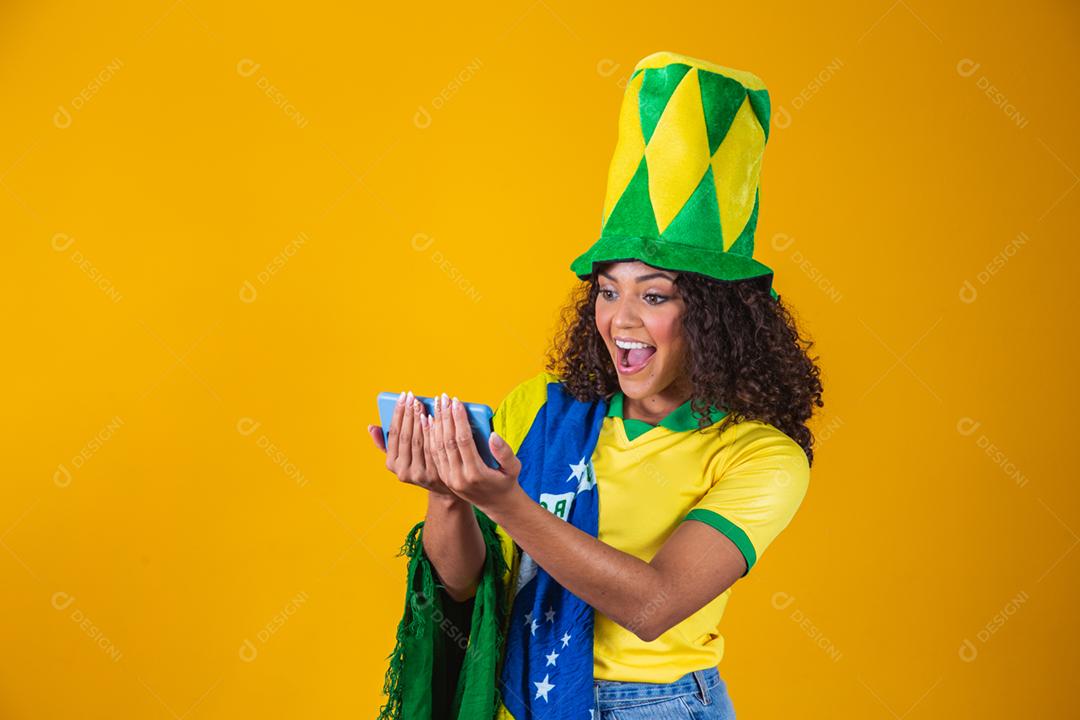 Garota afro torcendo pelo time brasileiro, segurando bandeira nacional