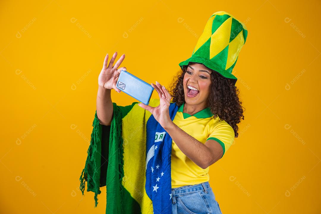 Garota afro torcendo pelo time brasileiro, segurando bandeira nacional