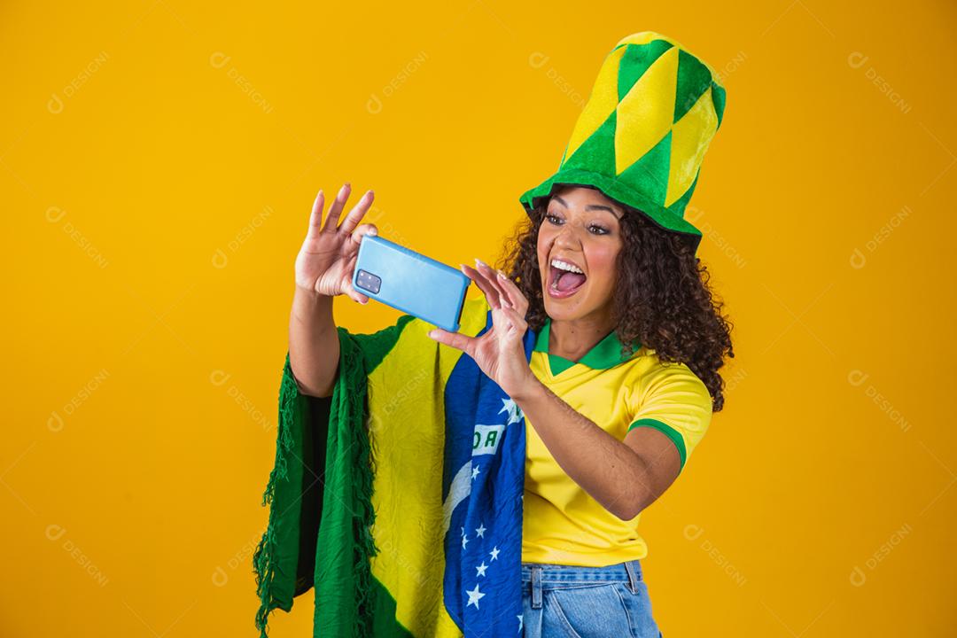 Garota afro torcendo pelo time brasileiro, segurando bandeira nacional