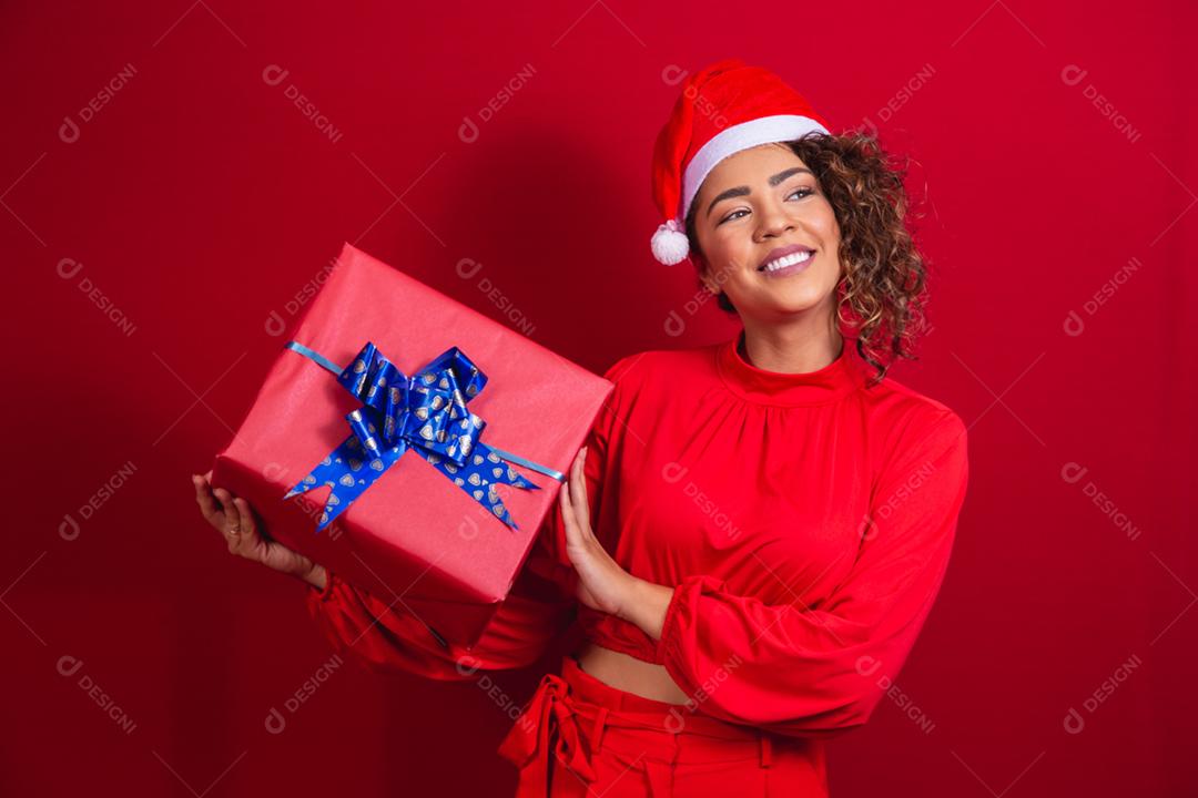 Retrato de jovem afro com chapéu de papai noel segurando um presente