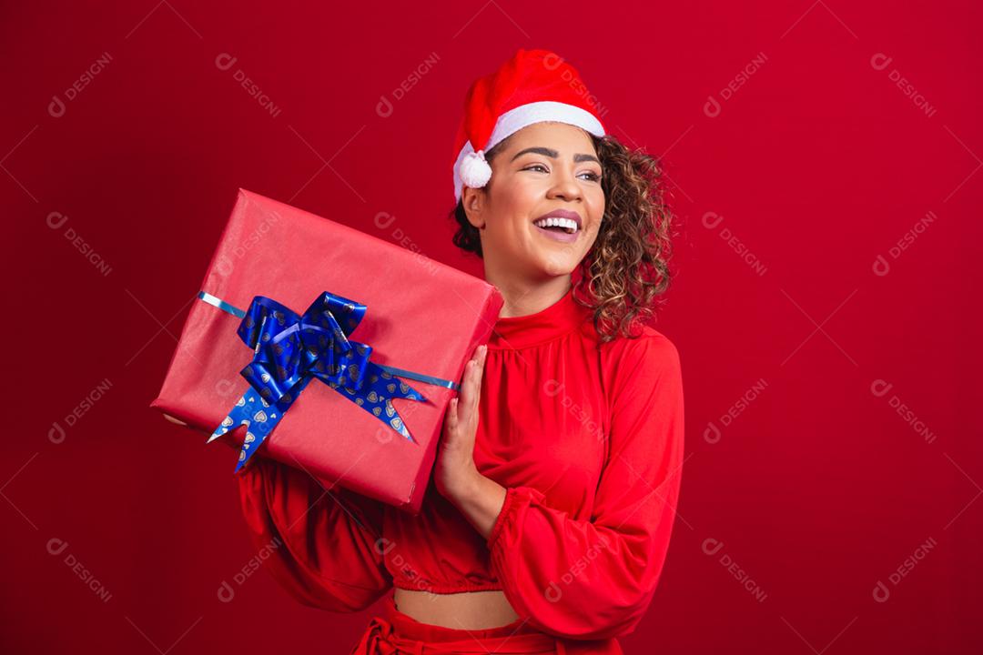 Retrato de jovem afro com chapéu de papai noel segurando um presente