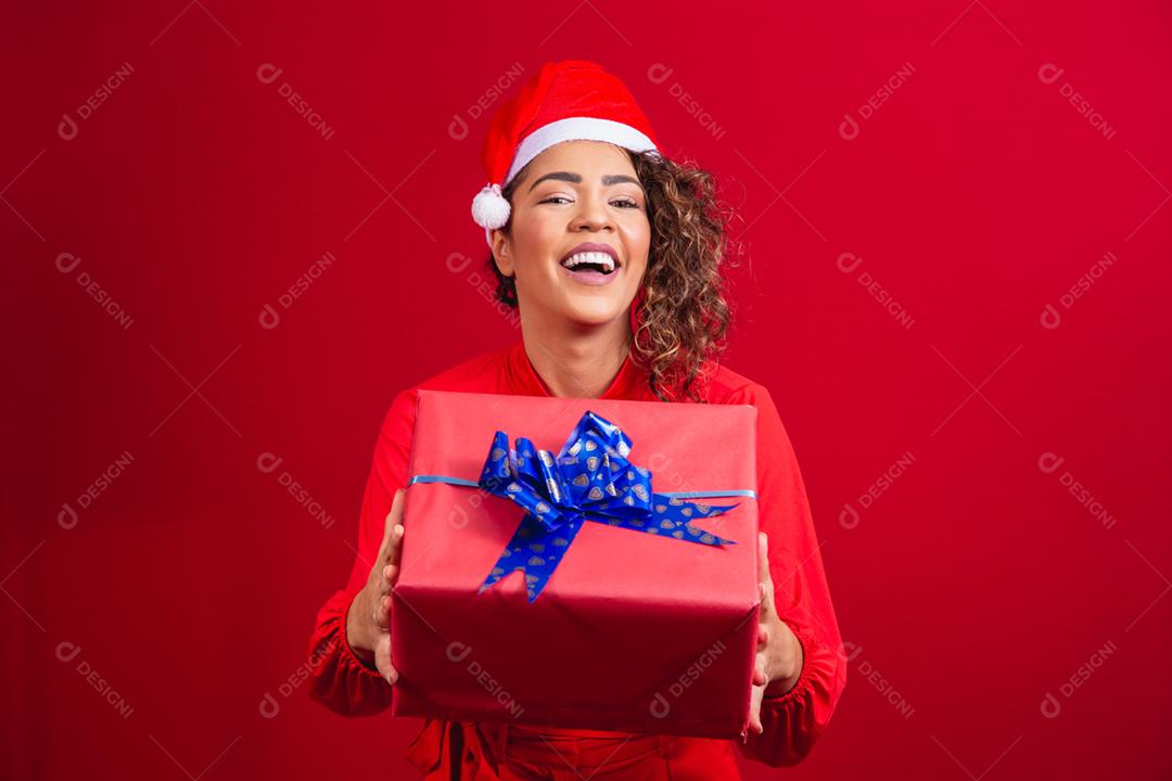 Retrato de jovem afro com chapéu de papai noel segurando um presente