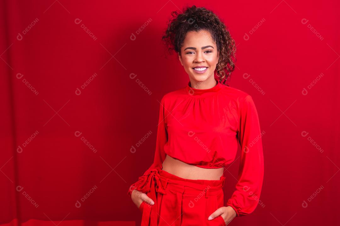 mulher afro sorrindo para a câmera em fundo vermelho
