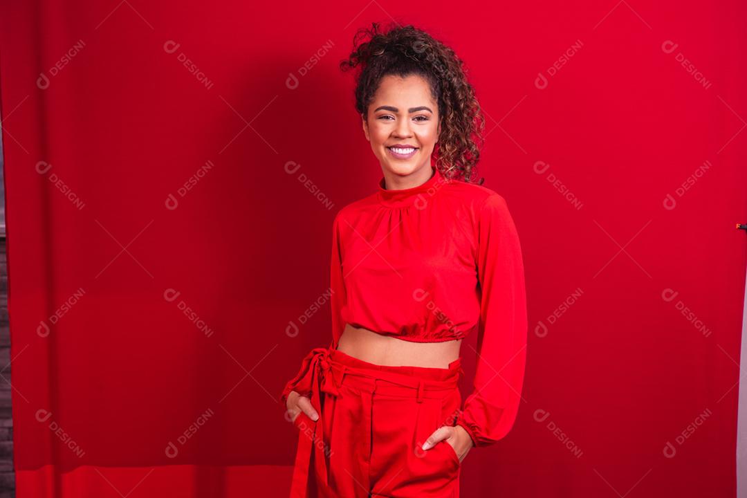 mulher afro sorrindo para a câmera em fundo vermelho