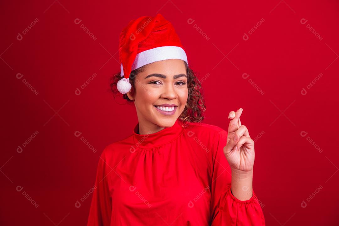 jovem com roupa de natal e chapéu de papai noel com os dedos