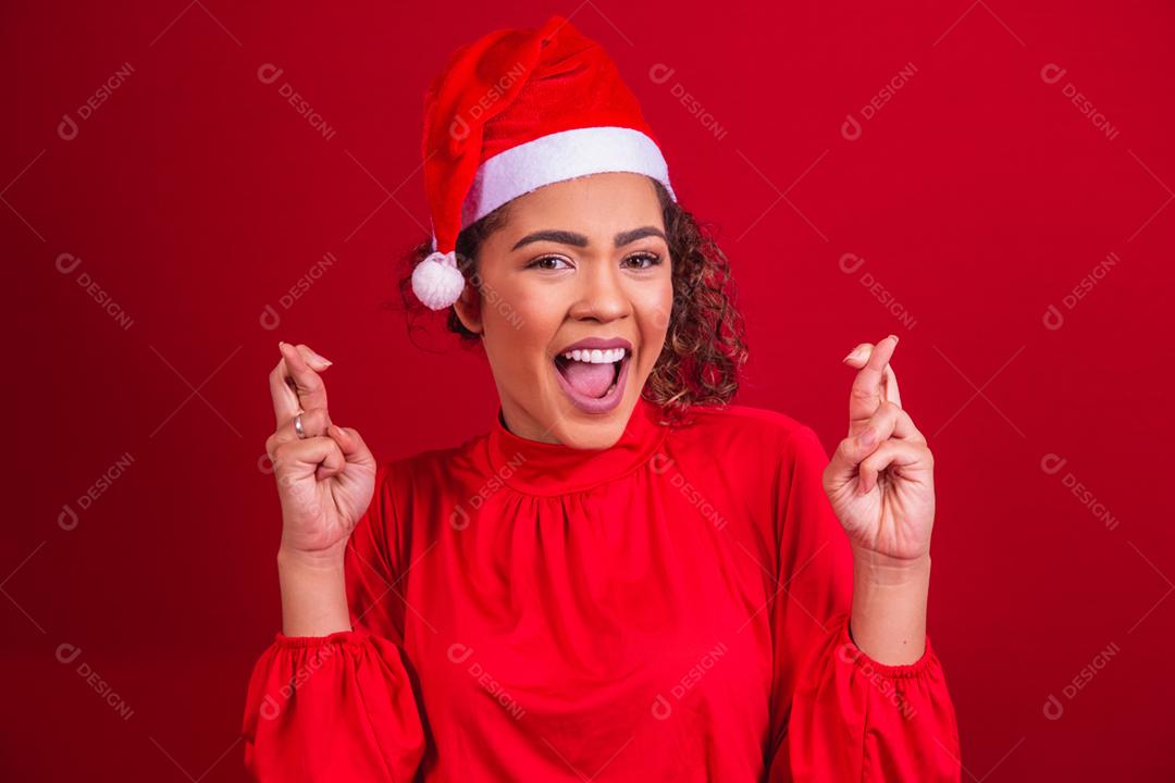 jovem com roupa de natal e chapéu de papai noel com os dedos