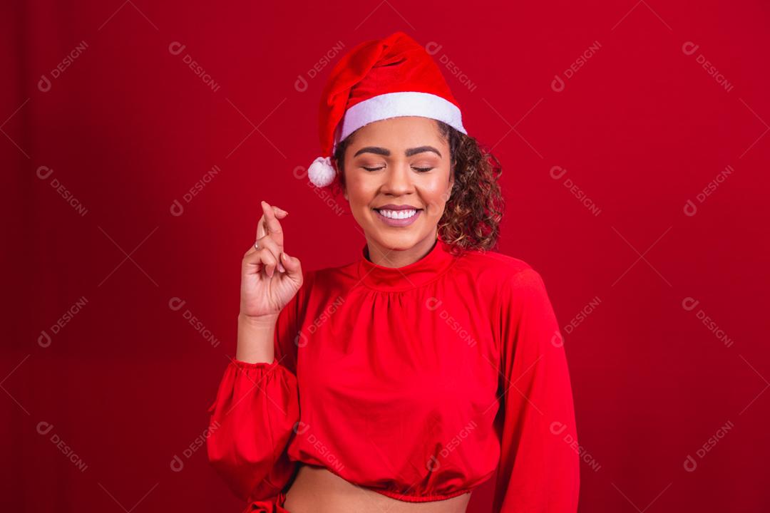 jovem com roupa de natal e chapéu de papai noel com os dedos