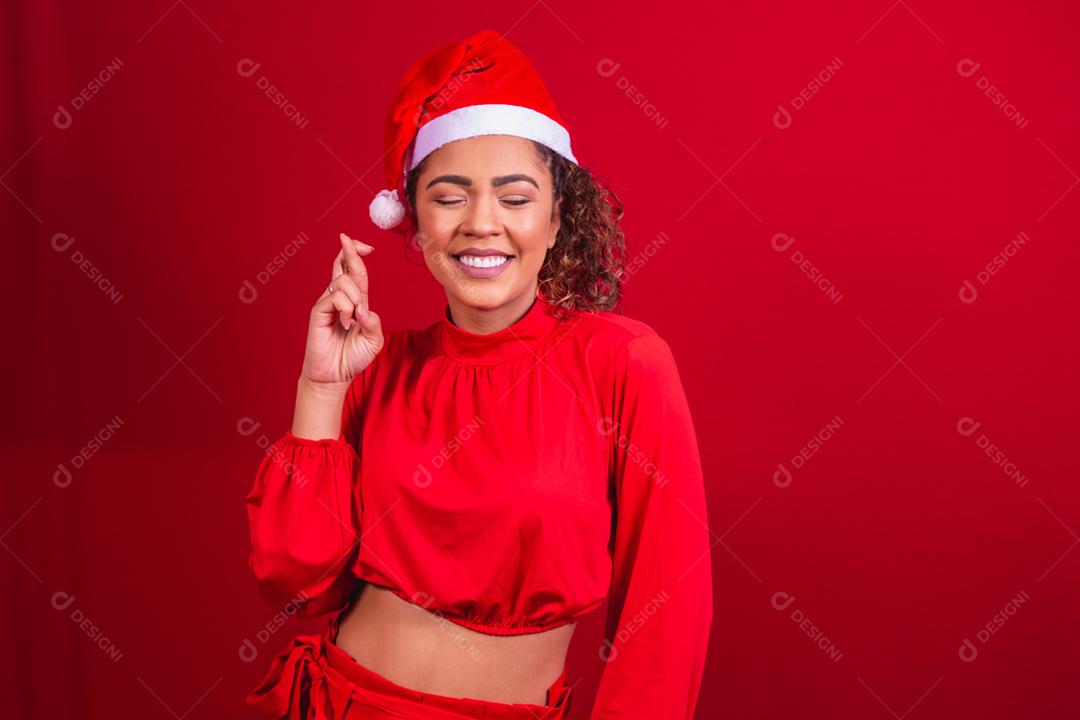 young woman in christmas outfit and santa claus hat with her fingers