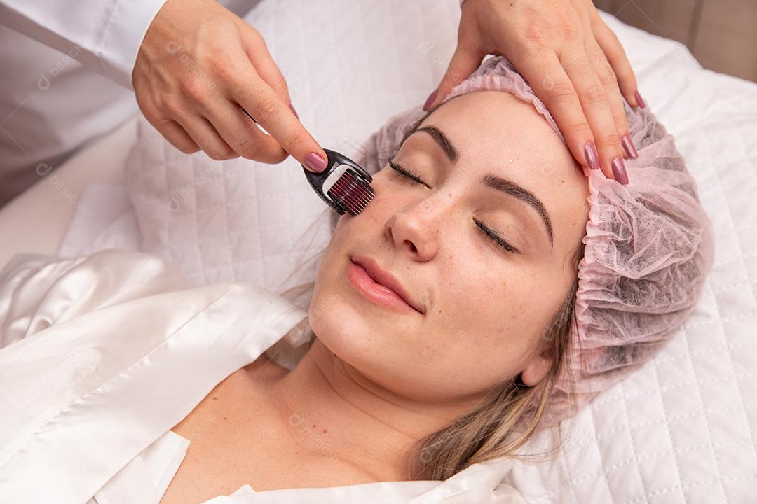 Rosto feminino de close up com dermaroller para procedimentos de mesoterapia