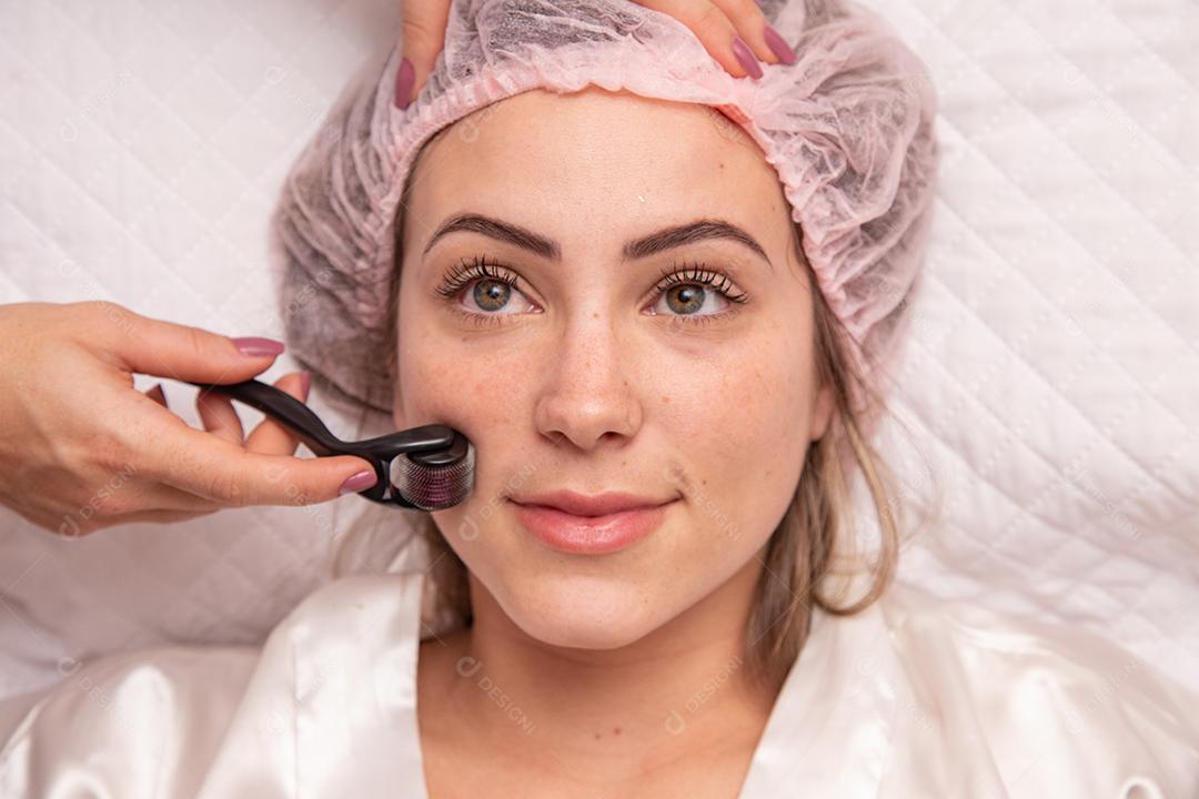 Rosto feminino de close up com dermaroller para procedimentos de mesoterapia